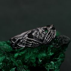 a silver ring sitting on top of a green rock