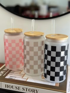 three different colored tumblers sitting on top of a book