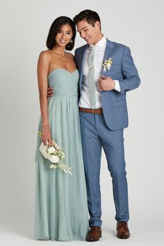 a man and woman in formal wear posing for a photo together, one is wearing a light blue suit