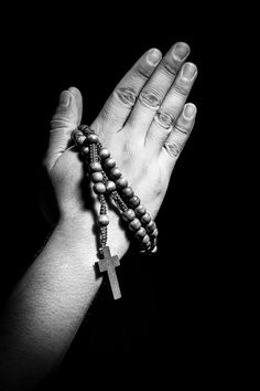 a woman's hand holding a rosary with a cross on the other side, in black and white