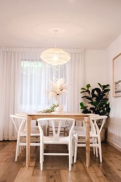 a dining room table with white chairs and a chandelier hanging from the ceiling