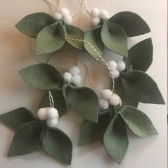 some green leaves and white balls hanging from it's sides on a wall ornament