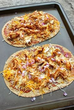 two pizzas sitting on top of a pan covered in toppings