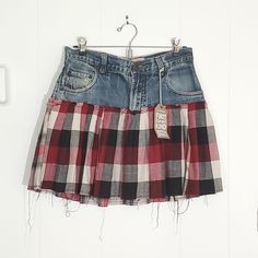 a red and black plaid skirt hanging on a white wall next to a pair of scissors