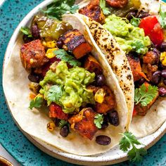 two tacos on a plate with black beans and guacamole