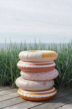 a stack of inflatable floats sitting on top of a wooden deck next to tall grass