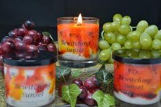 three candles sitting next to some grapes and other fruit on a table with the words bewitching sunset written on them