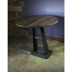 a wooden table sitting on top of a metal stand in front of a blue wall