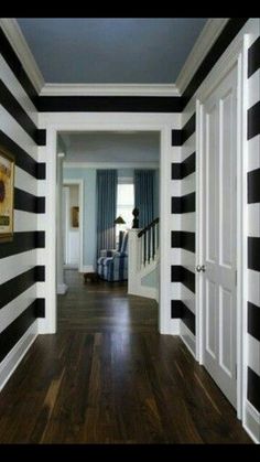 a hallway with black and white stripes painted on the walls, wood flooring and wooden floors