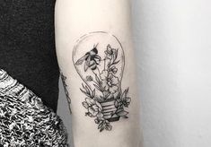 a woman with a tattoo on her arm has a bee and flowers in a light bulb