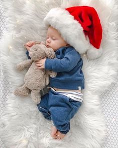 a baby sleeping with a teddy bear wearing a santa hat