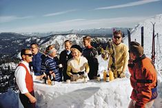 a group of people standing next to each other on top of a snow covered slope