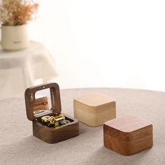 two wooden boxes with gold coins in them on a table next to a flower pot