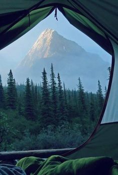 the view from inside a tent looking out at a mountain and trees in the distance