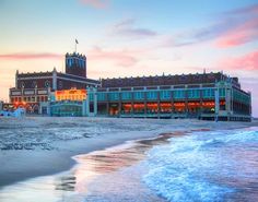 an ocean front building with a clock tower in the background at sunset or sunrise time