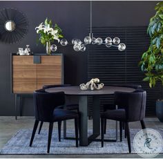 a dining room table with chairs around it and plants on the sideboard in front