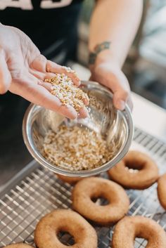 a person is sprinkling sugar on some doughnuts in a metal bowl