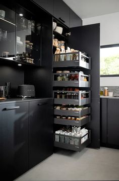 a kitchen with black cabinets and shelves filled with food, drinks and condiments