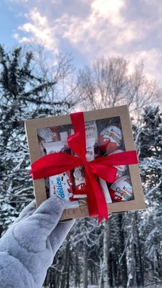 someone is holding up a box with some candy in it and red ribbon on the top