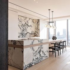 a kitchen with marble counter tops and black chairs in front of a large window that looks out onto the city