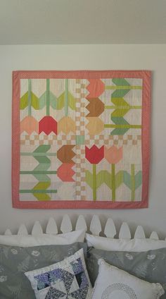 a quilt hanging on the wall above a bed