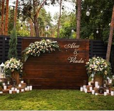 an outdoor wedding setup with candles and flowers on the grass, surrounded by wooden planks