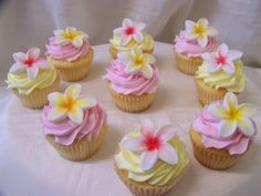 cupcakes decorated with pink and yellow flowers on a white tablecloth covered plate