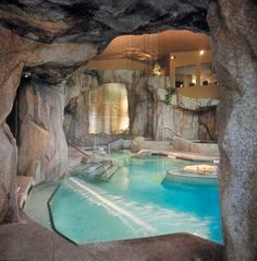 an indoor swimming pool surrounded by large rocks