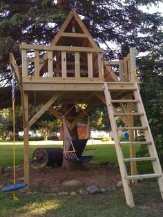 a wooden tree house with a ladder to the top