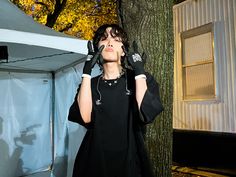 a woman standing next to a tree with her hands on her face and headphones in her ears