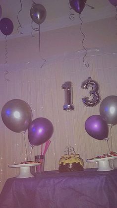 balloons and streamers are hanging from the ceiling in front of a table with a cake