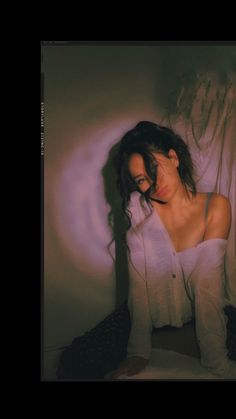 a woman is sitting on the floor in white clothing and boots with her hair blowing back