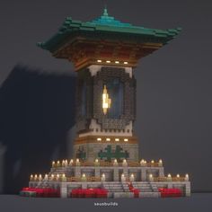 a tall tower with candles lit up in the middle of it's roof area