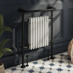 a white radiator sitting on top of a tiled floor next to a potted plant