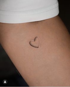 a small heart tattoo on the back of a woman's thigh