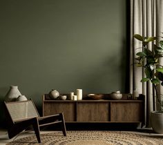 a living room with green walls and a rug in front of the window, next to a chair