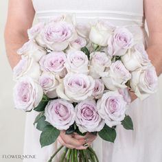 a woman holding a bouquet of white and pink roses