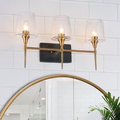 a bathroom with a mirror, sink and lights on the wall next to a potted plant