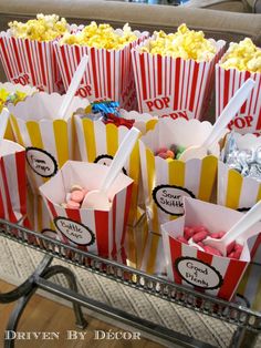 popcorn bags filled with candy sitting on top of a metal tray in front of a couch