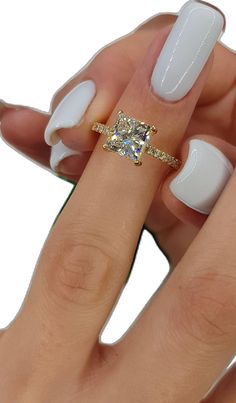 a woman's hand with white manicured nails and an engagement ring