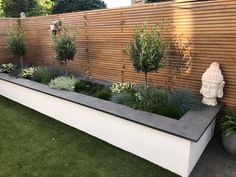 an outdoor garden with artificial grass, plants and buddha statue on the side of it