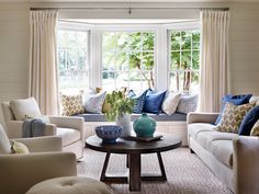 a living room with couches, chairs and a coffee table in front of a window