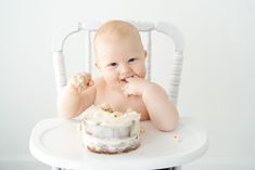 a baby sitting in a high chair eating cake