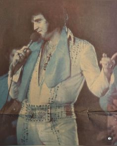 an old photo of elvis presley holding a microphone in his right hand and singing into the microphone