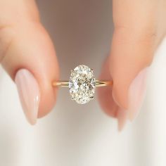 a woman's hand holding a ring with a diamond in it and the other hand behind her