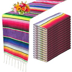 a stack of multicolored towels next to a bouquet of flowers on top of each towel