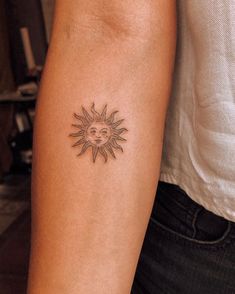 a woman's arm with a tattoo on it that has a sun in the middle