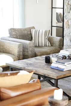 a living room with two couches and a coffee table in front of a stone wall