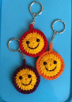 two crocheted smiley face key chains on a blue tray