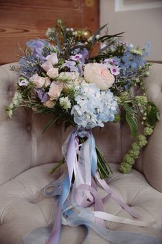 a bouquet of flowers sitting on top of a chair next to a ribbon tied around it